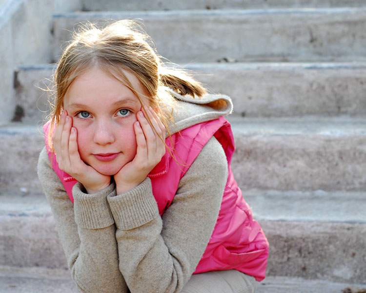 Bild på flicka som sitter på en trappa med hakan i händerna