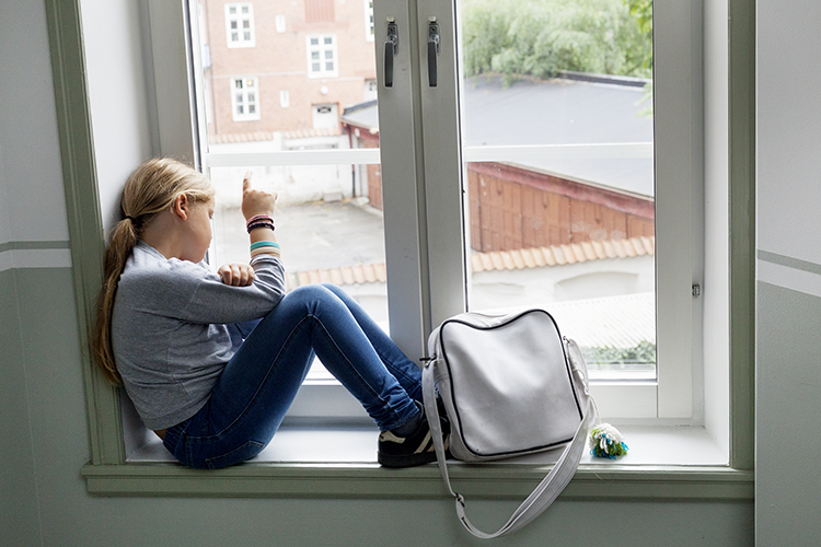 Tonårsflicka sitter i en fönstersmyg