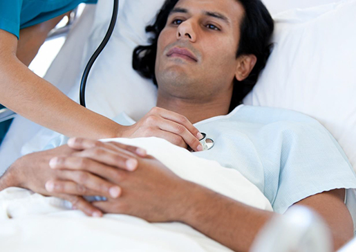 Vårdpersonal lyssnar med stetoskåp på patient i säng