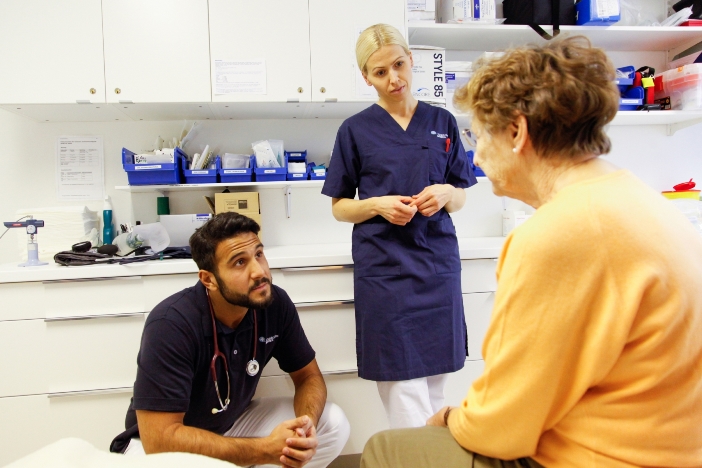 En kvinnlig och en manlig vårdpersonal pratar med kvinnlig patient En kvinnlig och en manlig vårdpersonal pratar med kvinnlig patient