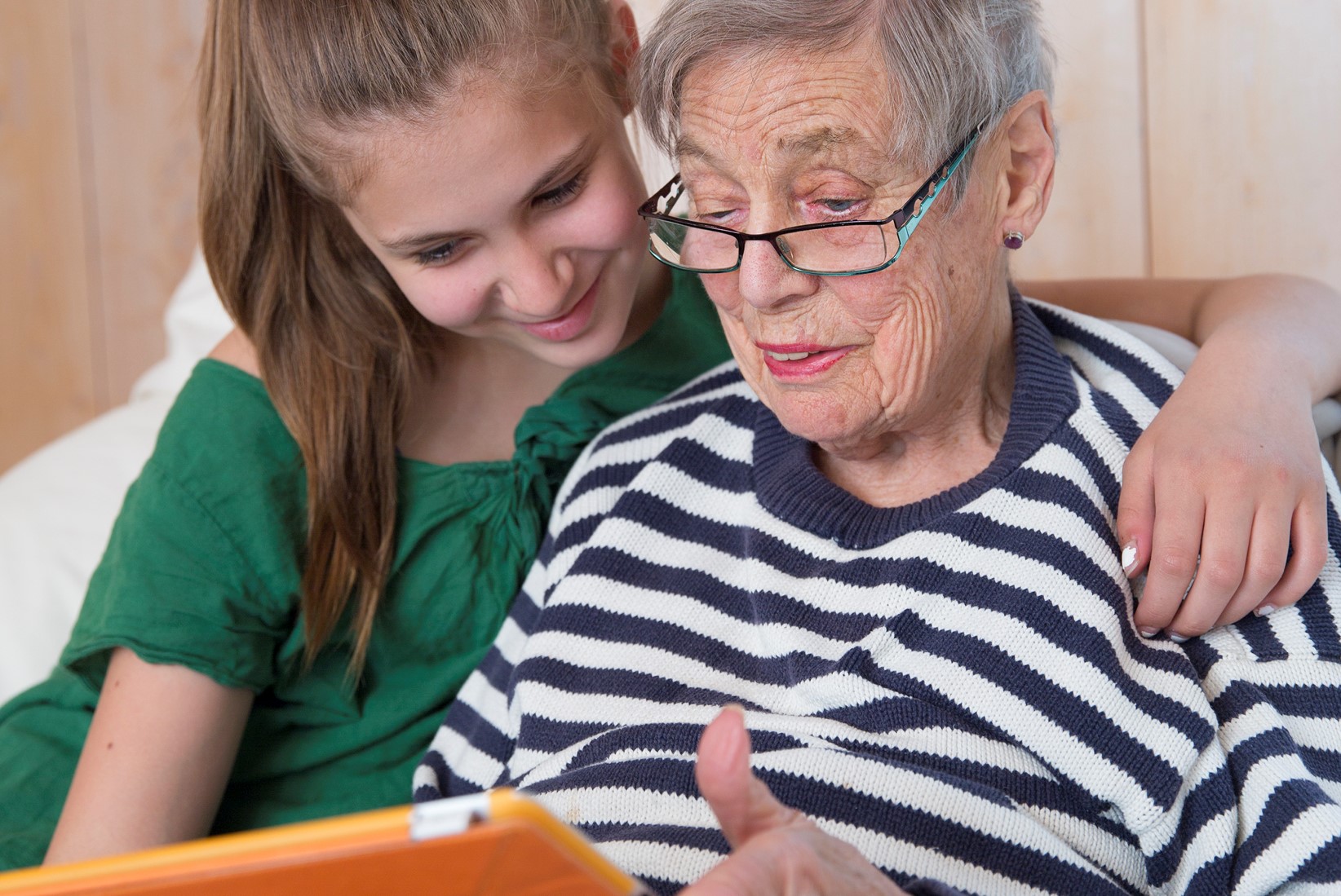 En ung person och en äldre person sitter med en datorplatta