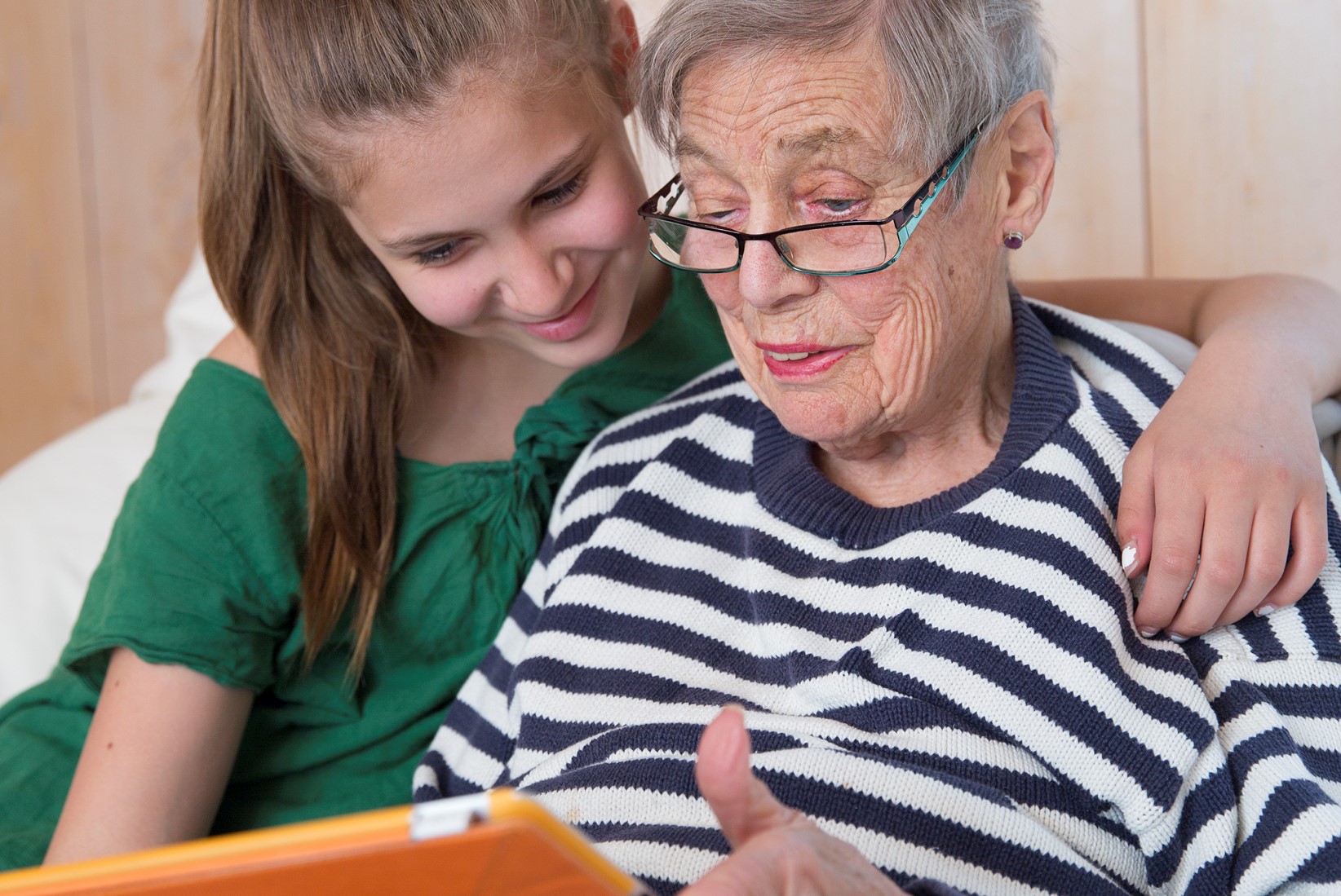 En ung person och en äldre person sitter med en datorplatta En ung person och en äldre person sitter med en datorplatta