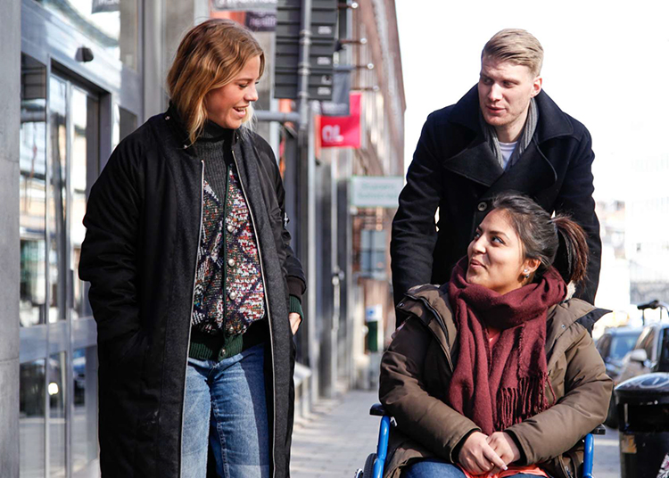 kvinna i rullstol pratar med kvinna och man