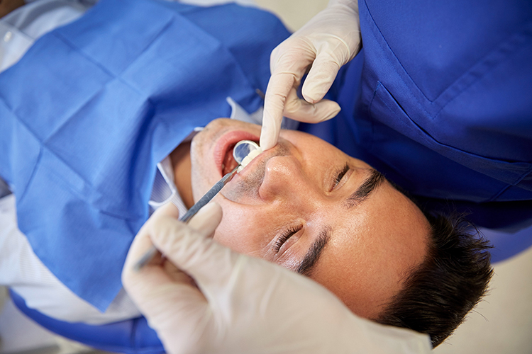Manlig patient blir undersökt av tandläkare.