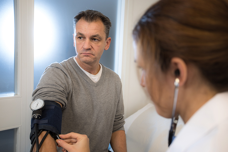 Kvinnlig vårdpersonal undersöker manlig patient. Kvinnlig vårdpersonal undersöker manlig patient.