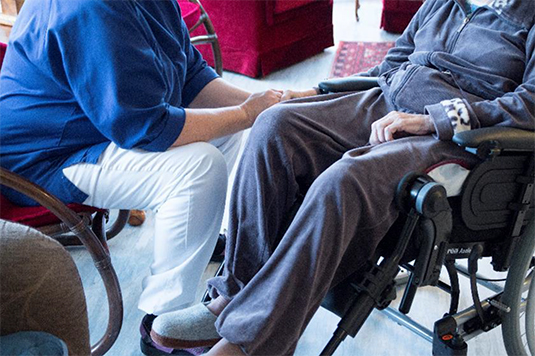 Person som håller en äldre person i rullstol i handen Person som håller en äldre person i rullstol i handen